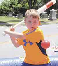 Ryder Linnens concentrates on swinging at the baseball at the Batter-Up game for kids during the Crossroads Festival.