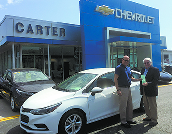 Mark Carter buys a Boys & Girls Club Car Raffle ticket from Club Board President Jack Weller. The winner this year will own a 2017 Chevrolet Cruze.