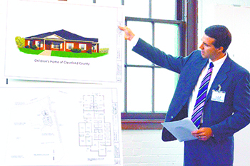 Justin Merritt, co-chair of the Children\'s Homes fund drive for $1.9M, points to a drawing of the proposed 7,350 foot building to go up next to the James Home site in Shelby. Jay Gragg, president of the CHCC board is co-chairman of the capital fund drive