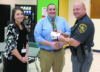 Lt. Steve McKee, right, presents a check to Jeremy Shields, center, and Erica Gardner, left, at Crest Middle School to help kids at Christmas.