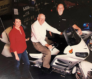 Honda of Shelby founder David Beam is seen on a Gold Wing touring bike with daughter Betty Ann Gibson and son Scott Beam.  Photo by Victorian Rose Studio