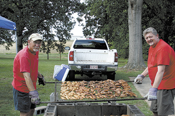 Out back, pitmaster John Abernethy slowly cooks his special barbecued chicken with the help of Eddie Padgett. John\'s been preparing this style of chicken for over 30 years.