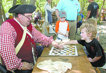 Chris Ivester member of the Backcountry Militia plays Drafts, which is what we now call playing checkers with Taylor Page at Kings Mountain National Military Park.