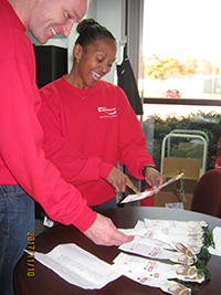 At Kendrion, Human Resources Manager Paula Vincent and Controller Wayne Longhurst check names and ages of Salvation Army Christmas angels available for their associates to adopt and shop for this holiday season.