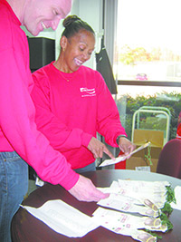 At Kendrion, Human Resources Manager Paula Vincent and Controller Wayne Longhurst check names and ages of Salvation Army Christmas angels available for their associates to adopt and shop for this holiday season.