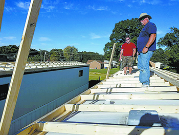 Adult volunteers work on a roof.