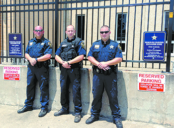 Three members of the Cleveland County Sheriff\'s Department stand in the area designated as a safe meeting zone for online transactions, child custody transfers, or any other meeting where those involved feel safer with video surveillance. Two cameras mon