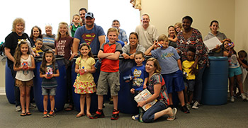 Moms, dads, grandmoms and kids show off their rain barrels made during a summer reading program while learning about collecting rain water and its benefit for our flowers and plants.