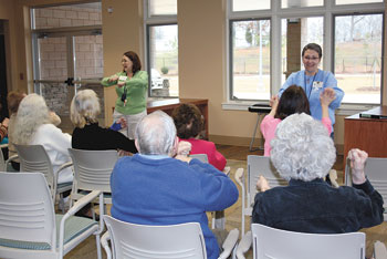 Two program assistants direct adults through a special exercise program.