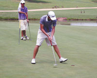 Chad Cox sinks yet another putt to make par on the 18th hole as Zachary Bauchou watches.