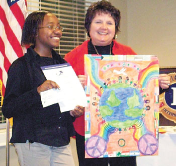 Lion  Barbara Fitch holds  the winning peace poster designed by Tori  Owens.