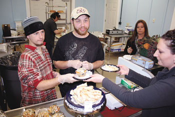 Stephanie Davis is served a fresh baked blueberry muffin and cinnamon twist by Steven Blanton, left & Isaiah Warren, right. Louise Dowell, and Shelly Packer in background.