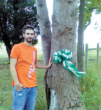 Allen White stands by the tree he hit on September 3, 2004. The ribbon is a marker for the â€œRide For The Mindâ€ motorcycle event.