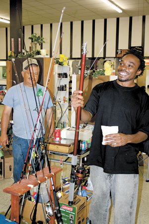 Travis Mitchell (right) admires some deep sea tackle at Todd Lailâ€™s booth inside. Todd (left) specializes in selling all types of fishing equipment.