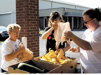 Chrissy Helton and Chrystal Grier (right) accept some beautiful yellow squash from Peggy Price for distribution.