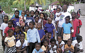 Rev. Marc Brice with some of the many children his ministry  helps in the still ravished island of Haiti.