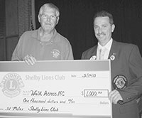 Lion Dave Titus (left)  presents a check for $1,000 to District Governor Robert Suggs.