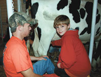  Burns student Jonathan Williams, teaches ten year old  Andrew how to milk a cow. 