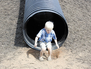 Camron, age 6, exits the pipe slide. He enjoyed it so much  this was his third time  going down the slide.
