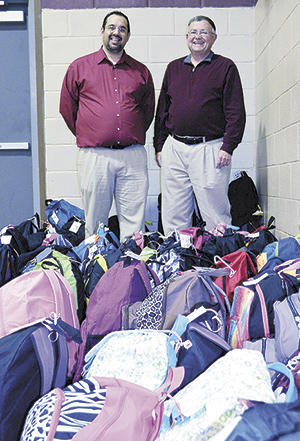 Pastor Mark Akers of Freedom Community Church in Pennsylvania (left) and Allan Barlow, Pastor of Zion Hill Baptist Church in Lawndale stand with the 'mountain' of backpacks before giving them out during a community outreach party.