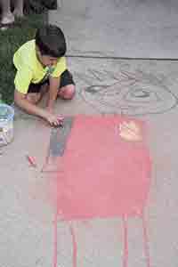 Andrew Bumgardner draws a chalk Ninja on the sidewalk.